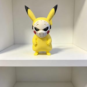 May include: A yellow figurine of a creature with long ears tipped in black, wearing a white hockey-style mask with ventilation holes over its face. The character has red circular cheeks and a smooth, matte finish, standing in an upright position.