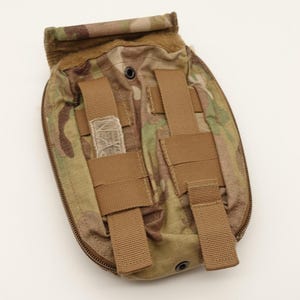 Peut inclure: Une pochette tactique avec un motif camouflage multicolore dans des tons de beige, marron et vert. L'extérieur comprend deux sangles de fixation verticales en nylon marron, un rabat supérieur avec fermeture auto-agrippante et un œillet.
