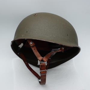 May include: A white ceramic mug with a black handle and the text "But First, Coffee" in a bold, black font. The mug is set against a blurred background, suggesting a cosy setting.