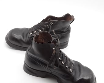 Op de afbeelding: Een paar zwarte leren wandelschoenen met veters en metalen oogjes. De schoenen hebben een robuuste uitstraling en zijn gemaakt van hoogwaardig leer.