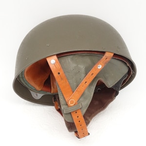 May include: A green military helmet with a brown leather strap and liner. The helmet is in good condition and has a few minor scratches.