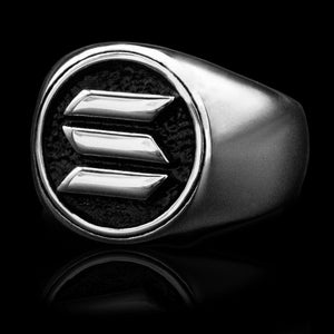 Può includere: Un anello a sigillo in argento con un'incisione in smalto nero che presenta un design stilizzato a tre barre.
