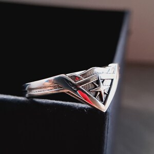 Pu&ograve; includere: Un anello d'argento con un design a stella stilizzato. L'anello ha la forma di un triangolo con una punta appuntita.