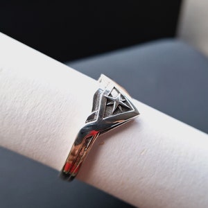 Pu&ograve; includere: Un anello d'argento con un design triangolare che presenta una stella al centro.