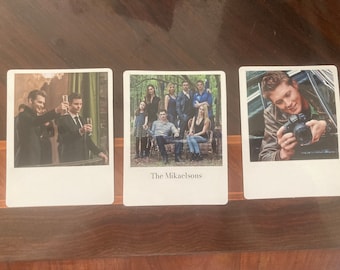 Puede incluir: Tres fotos de estilo Polaroid, cada una con un grupo diferente de personas. La primera foto muestra a dos hombres con traje brindándose con copas de champán. La segunda foto muestra a un grupo de personas, incluyendo un hombre sentado en una silla, una mujer de pie detrás de él y una mujer sentada en una silla frente a él. El texto "The Mikaelsons" está impreso debajo de la foto. La tercera foto muestra a un hombre sosteniendo una cámara y mirando al objetivo de la cámara.