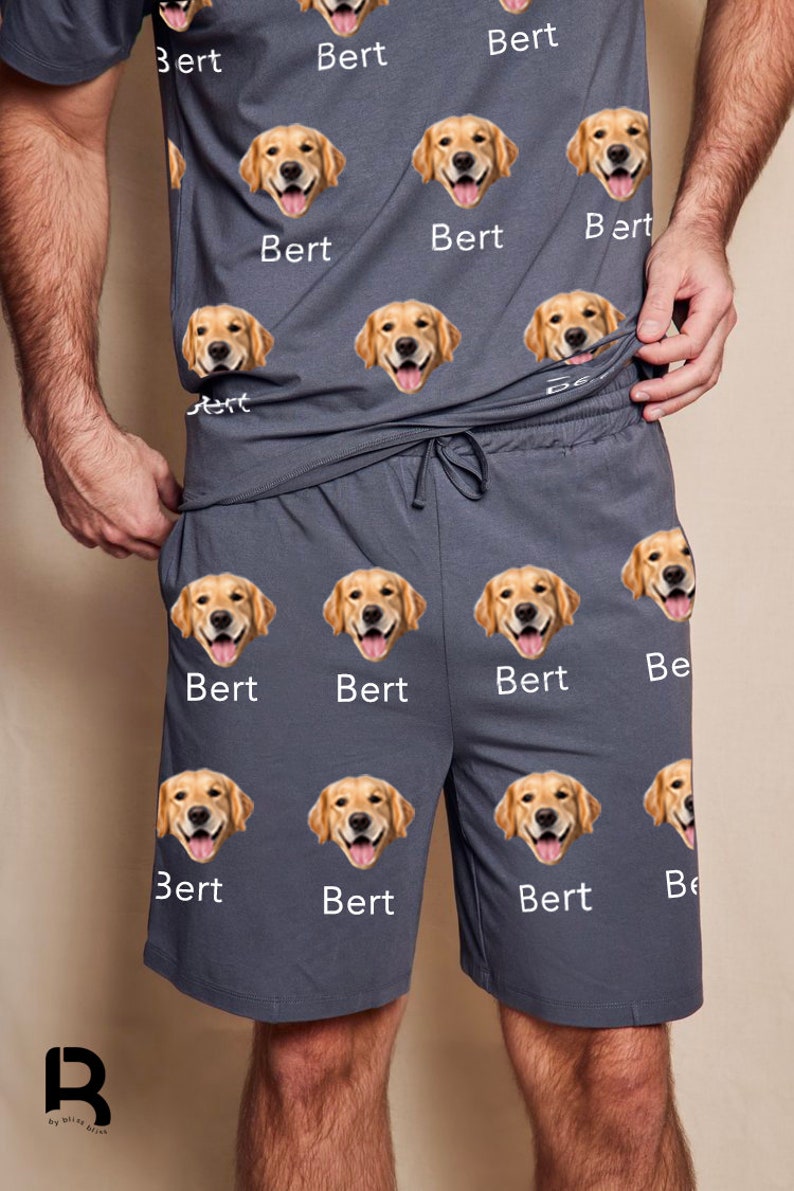 Pu&ograve; includere: Un pigiama grigio con un motivo ripetuto di un viso di golden retriever e il nome "Bert" stampato sulla maglietta e sui pantaloncini.