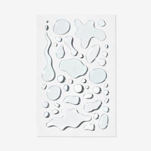 Puede incluir: Una hoja de papel blanca con múltiples gotas de agua transparentes y translúcidas de varios tamaños y formas.