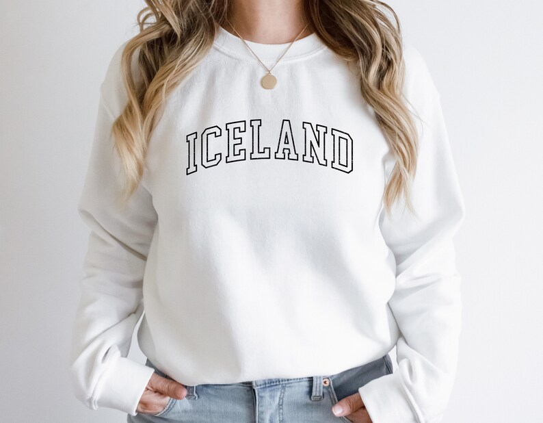 May include: White sweatshirt with black text that reads "ICELAND" in a collegiate font.