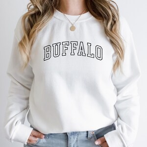 May include: White sweatshirt with black text that reads "BUFFALO" in a collegiate font.