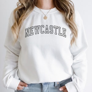May include: White sweatshirt with black text that reads "NEWCASTLE" in a collegiate font.