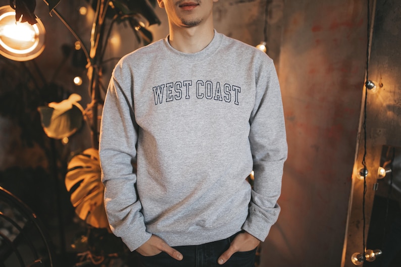 May include: A gray sweatshirt with the text "WEST COAST" in blue outlined letters.