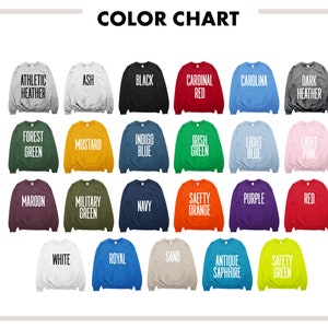 May include: Color chart showing 24 different sweatshirt colors. The colors are displayed in a grid of 4 rows and 6 columns. The colors include athletic heather, ash, black, cardinal red, carolina blue, dark heather, forest green, mustard, indigo blue, irish green, light blue, light pink, maroon, military green, navy, safety orange, purple, red, white, royal blue, sand, antique sapphire, and safety green.