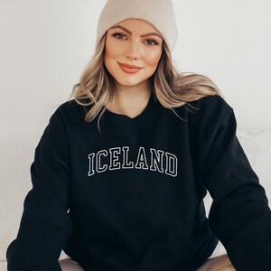 May include: Black sweatshirt with white text that reads "ICELAND" in a collegiate font.