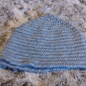 Puede incluir: Un gorro de punto azul claro. El gorro está hecho de un hilo suave y peludo.