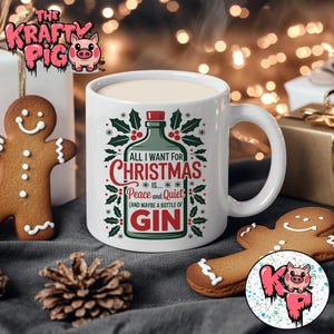 May include: White ceramic mug with a Christmas design. The mug has the text "ALL I WANT FOR CHRISTMAS IS... Peace and Quiet (AND MAYBE A BOTTLE OF GIN)" in red and green. A gingerbread man and a pine cone are also visible.
