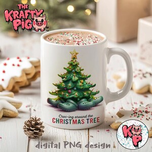 Puede incluir: Taza de cerámica blanca con un árbol de Navidad verde y adornos rojos y blancos. El árbol está rodeado de Crocs verdes, azules y amarillos. El texto "Croc-ing around the CHRISTMAS TREE" está impreso en la taza.
