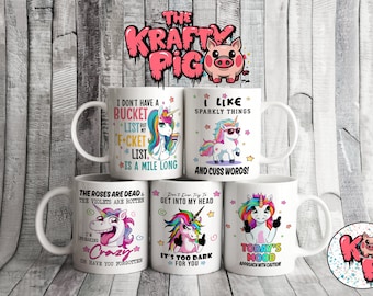 May include: White ceramic mugs featuring unicorn illustrations and funny quotes. One mug says "I don't have a bucket list but my f*cket list is a mile long." Another says "I like sparkly things and cuss words!"
