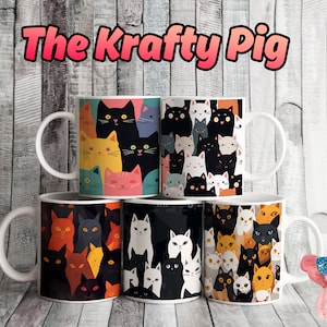 May include: Six white ceramic mugs with different cat designs. The mugs are stacked in a pyramid shape. The mugs are all white with a black handle. The cat designs are all different colors and patterns. The mugs are on a wooden surface. The text "The Krafty Pig" is at the top of the image.