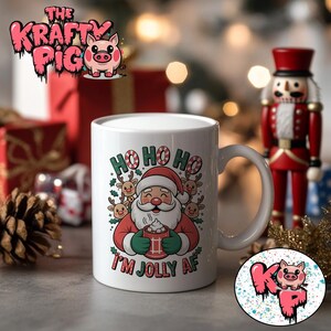 May include: White ceramic mug with a Santa Claus graphic, featuring the text "HO HO HO" and "I'M JOLLY AF". The design includes reindeer and Santa holding a mug. A festive holiday-themed mug.