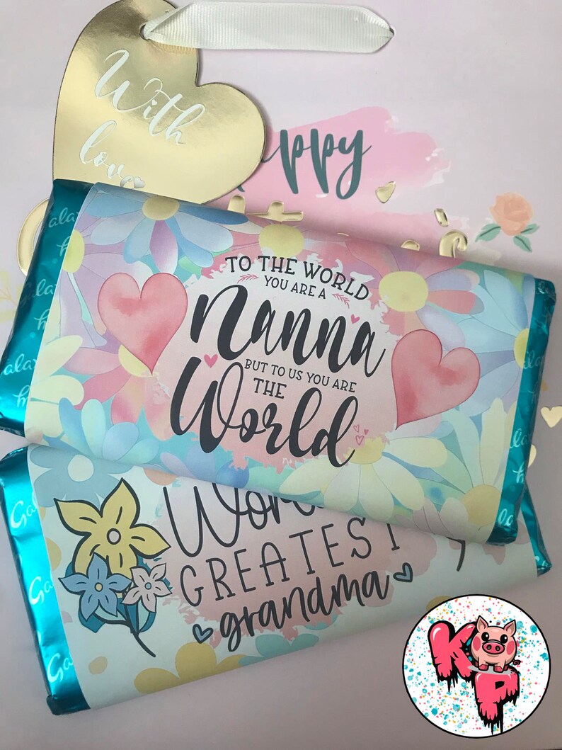Pode incluir: Duas barras de chocolate com um design floral e uma mensagem para uma av&oacute;. A barra superior diz "Para o mundo voc&ecirc; &eacute; uma Nanna, mas para n&oacute;s voc&ecirc; &eacute; o mundo". A barra inferior diz "A melhor av&oacute; do mundo".