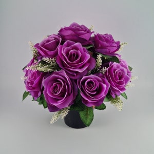 May include: A bouquet of purple silk roses arranged in a black pot. The roses are in full bloom and have a realistic appearance.