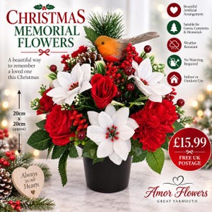 May include: A Christmas memorial flower arrangement in a black pot featuring white poinsettias, red roses, red berries, a pinecone, and a robin figurine. The text reads CHRISTMAS MEMORIAL FLOWERS and Always in our Hearts. It measures 20cm x 20cm.