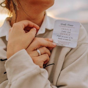 May include: A square white card with rounded corners featuring the text Breath Prayer, Inhale Creator God, Exhale Make me aware of the beauty around me, and The spirit of God has made me; the breath of the almighty gives me life Job 33:4.