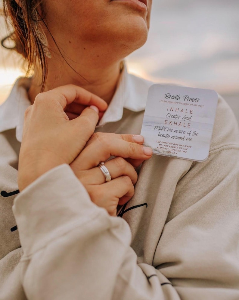 May include: A square white card with rounded corners featuring the text Breath Prayer, Inhale Creator God, Exhale Make me aware of the beauty around me, and The spirit of God has made me; the breath of the almighty gives me life Job 33:4.