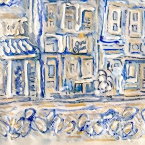 Op de afbeelding: Een gedetailleerd, getextureerd reli&euml;fsculptuur dat een straatbeeld weergeeft met gebouwen in blauw, wit en goud. Het kunstwerk toont architectonische details, winkelpuien en decoratieve elementen, waardoor een driedimensionaal effect ontstaat.