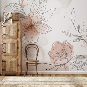 Pu&ograve; includere: Un armadio in legno con tre ante e una sedia di fronte. La parete dietro l'armadio e la sedia &egrave; decorata con una carta da parati floreale con accenti acquerellati rosa e grigi.
