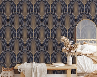 May include: A bedroom interior with a navy blue and gold geometric patterned wallpaper. A wooden bench with a white throw blanket sits in front of the wallpaper. A bed with a white duvet and a brown throw blanket is in the background. A vase with dried flowers sits on the bench.