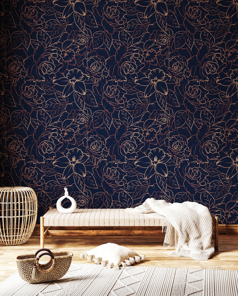 Peut inclure: Un papier peint bleu marine avec un motif floral dor&eacute; repr&eacute;sentant des roses et des lys. Le papier peint est pr&eacute;sent&eacute; dans une pi&egrave;ce avec un banc en bois, un panier en osier et une couverture blanche.