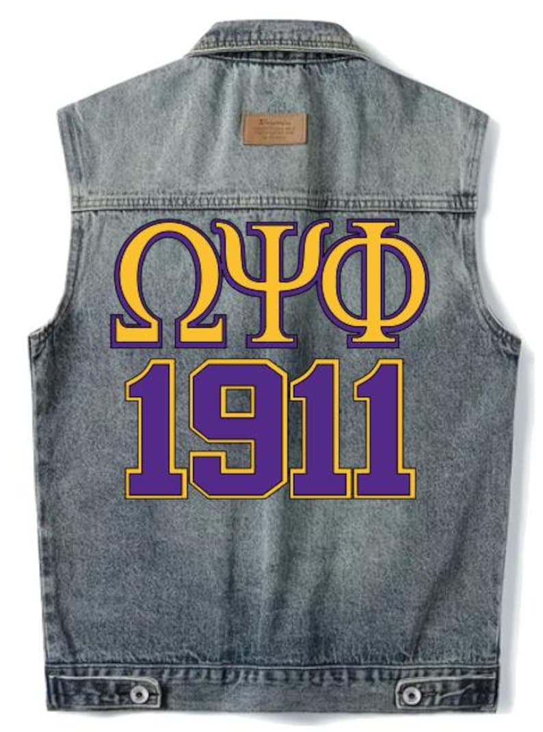 May include: A sleeveless denim jacket with a faded wash. The back features the Greek letters Omega, Psi, and Phi in gold with a purple outline, above the number 1911 in purple with a gold outline. A small brown tag is at the top.