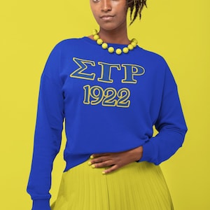 May include: A royal blue sweatshirt with a yellow outline of the letters "ΣΓΡ" and the year "1922" printed on the front.
