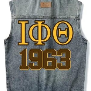 Peut inclure: Un gilet en jean sans manches avec les lettres grecques IΦΘ et le chiffre 1963 en marron et or. Le gilet a un délavage en jean classique et une petite étiquette marron.