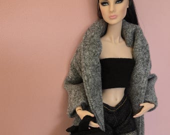 May include: A fashion doll wearing a grey coat, a black bandeau top, denim shorts, and a black backpack.