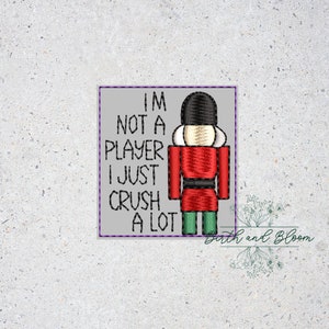 May include: A gray square with a white border and the text "I'm not a player I just crush a lot" with a cartoon nutcracker in a red and green uniform.
