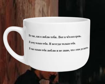 Könnte beinhalten: Ein weißer Keramikbecher mit schwarzem kyrillischem Text, der lautet: "Не так, как я люблю тебя. Вот в чём вся хрень. Я хочу только тебя. И всегда только тебя. Я так сильно тебя люблю и не знаю, что с этим делать." Der Becher hat einen runden Körper und einen Henkel.