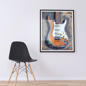 May include: A framed print of a vintage electric guitar with a worn, distressed finish. The guitar is painted in shades of orange, brown, and blue, with a white pickguard and chrome hardware.