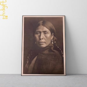 May include: Framed sepia-toned portrait of a Native American woman. She has long, dark hair, and is wearing earrings and a dark shawl. The image is a close-up, showing her face and upper body.