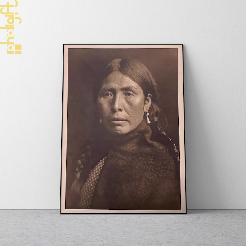 May include: Framed sepia-toned portrait of a Native American woman. She has long, dark hair, and is wearing earrings and a dark shawl. The image is a close-up, showing her face and upper body.
