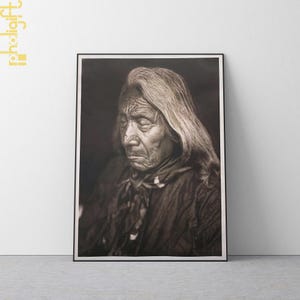 May include: A framed sepia-toned portrait of an elderly person with long, flowing gray hair. The subject, with a weathered face, is wearing a dark garment and a patterned scarf. The image is set against a plain white wall.