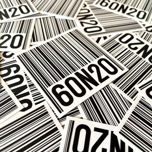 May include: A close-up of a pile of white stickers with black barcode patterns and the text "60N20" printed on them.
