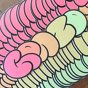 May include: A stack of colorful stickers featuring a three-dimensional design of three connected swirls in pink, orange, and green. The swirls are outlined in black.