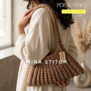 May include: A tan crochet shoulder bag with a ribbed design. The bag has a long, thick strap and a small tag that says "Mira Stitch". The text "PDF & VIDEO CROCHET PATTERN" is in the upper right corner. The text "MIRA STITCH" is at the bottom.