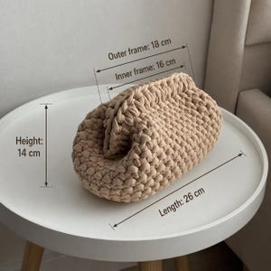 Finished chunky crochet pouch with measurement lines showing the size on a round white table.