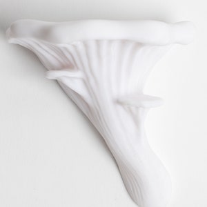 Op de afbeelding: Witte keramische sculptuur van een paddenstoel met een getextureerd oppervlak.