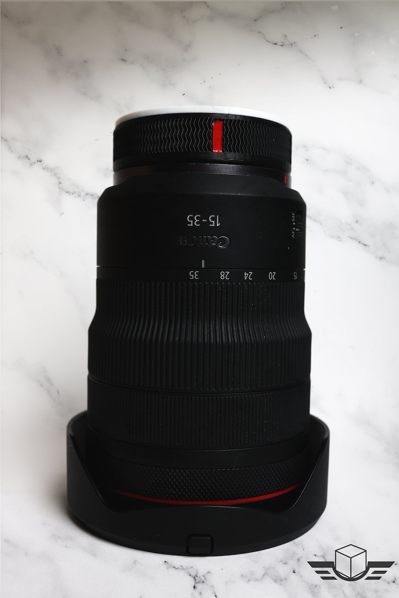Pu&ograve; includere: Un obiettivo Canon 15-35 mm nero con una fascia rossa attorno al barilotto. L'obiettivo ha una ghiera di zoom con le indicazioni per 15, 20, 24, 28 e 35 mm.