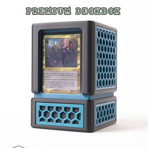 May include: A black and blue 3D printed deck box with a hexagonal pattern. The box is designed to hold a standard Magic: The Gathering trading card. The card in the box is "Urea, the Cruel Harbinger", a legendary creature with affinity for artifact creatures. The card text reads: "Affinity for artifact creatures (This spell costs 1 less to cast for each artifact creature you control). Artifact creatures you control have menace. At the beginning of your end step, create a 0/0 colourless Construct artifact creature token with "This creature gets +1/+1 for each artifact you control."