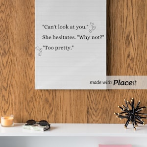 May include: A white canvas with a handwritten quote: "Can't look at you." She hesitates. "Why not?" "Too pretty." The canvas is hanging on a wood wall above a white shelf with a candle, sunglasses, a book, and a pink notebook.